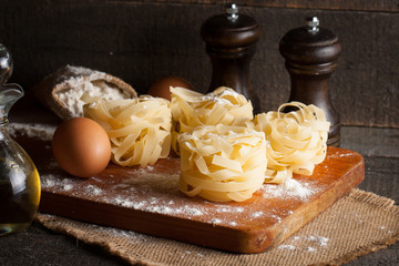 Closeup of raw homemade pasta with ingredients on wooden, rustic background. Pasta, salt, eggs, yolk, pepper. Home made food concept.