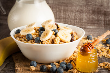 Healthy breakfast concept with oat flakes and fresh berries on rustic background. Food made of granola and muesli. Healthy banana smoothie with blackberries, honey and milk.