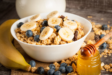 Healthy breakfast concept with oat flakes and fresh berries on rustic background. Food made of granola and muesli. Healthy banana smoothie with blackberries, honey and milk.