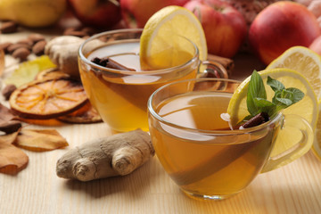 Autumn composition with hot tea, fruits and yellow leaves on a natural wooden table