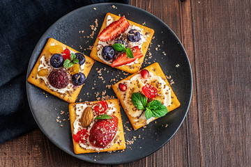 Set of crackers with various fruit close-up on black plate