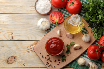 Red sauce in a bowl with fresh ingredients, tomatoes, garlic and oil and spices on a natural wooden table. view from above