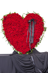 Funeral wreath of red roses in the shape of a heart, isolated on white background