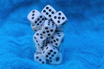 one small transparent plastic cup with white play bones on blue wool fabric