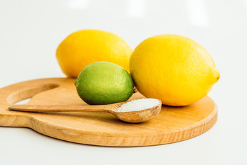 two lemons, lime and a wooden spoon with salt