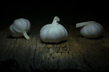 tre teste d'aglio su tavolo di legno con luce da studio, light painting