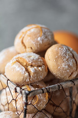 Homemade orange crinkle cookies with powdered sugar icing on gray background, vertical composition