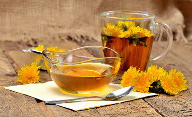 Dandelion honey, herbal tea, spoon and dandelion head around