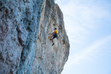 View of man without helmet hanging on a rope while rappelling and shows flying pirouettes in the...