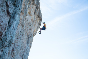 View of man without helmet hanging on a rope while rappelling and shows flying pirouettes in the air  © pablobenii