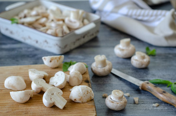 Whole and sliced mushrooms and mint leaves on wooden table.