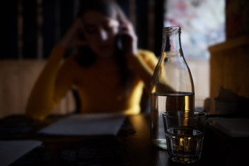 a glass cup and a bottle of water on the background of a busy girl talking on the phone