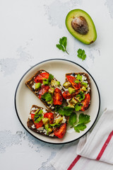 Avocados, cherry tomatoes and feta cheese sandwiches with balsamic sauce and cilantro on old olive board. Top view.