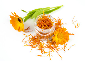  Dried Calendula officinalis the pot marigold, ruddles, common marigold or Scotch marigold,  plant blossom petals in transparent clear glass jar with fresh blossoms isolated on white background. 