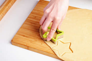 the process of making christmas cookies, raw dough, rolling pin and baking star forms.
