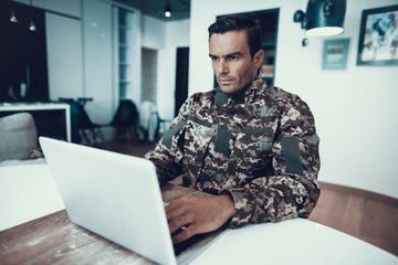 Handsome Military Man Works at Table on Laptop