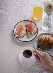 Continental breakfast captured from above (top view, flat lay). Coffee, orange juice, croissant, sandwich and flowers. Copy space.