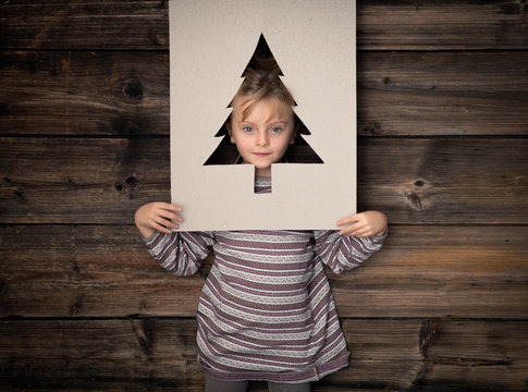 Text or logo empty copy space,vertical top view dark vintage wood.Happy child girl in homewear with cardboard tree pine.Childhood concept.Xmas winter holiday season party social media card background