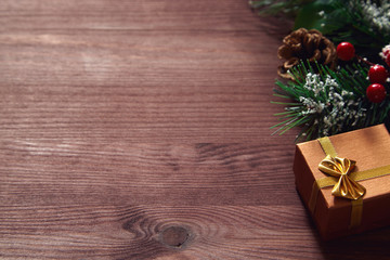 Fir tree branches, red berries and present box on wooden surface. Christmas and new year background.