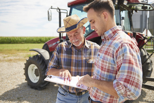 Farmers looking at data from clipboard on farm