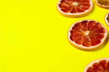 Scattered dried slices grapefruit and lemon on yellow background with copy space