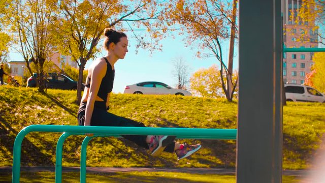 Female professional dancer performing choreographic exercises on parallel bars outdoors. Sunny day, golden autumn
