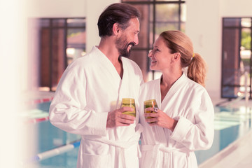 Happy relationships. Delighted positive couple smiling to each other while holding their drinks
