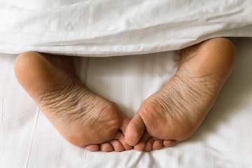 Feet of human legs protrude from under the blanket.