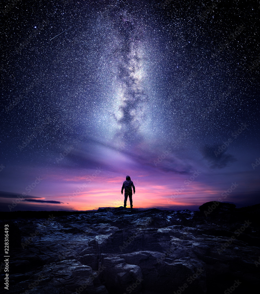 Wall mural night time long exposure landscape photography. a man standing in a high place looking up in wonder 