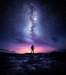 Fototapeten Landschaftsfotografie mit Langzeitbelichtung bei Nacht. Ein Mann, der an einem hohen Ort steht und verwundert zur Milchstraße blickt, Fotokomposit. © James Thew