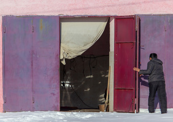 A man opens the gate in the garage in winter