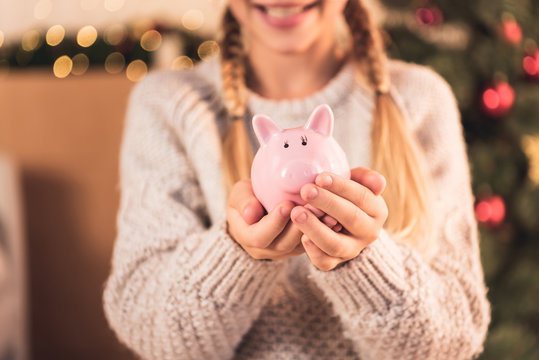 cropped view of female youngster holding pink piggy bank