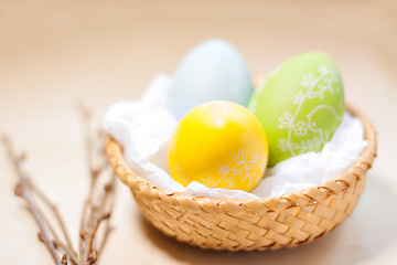 Colored easter eggs in nest on rustic wooden planks with branch