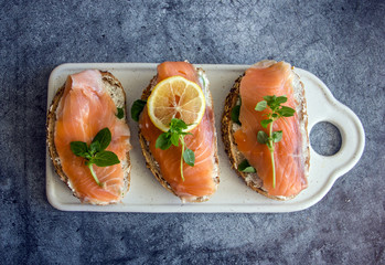Sandwices with salted salmon and soft white bread cheese, decorated with a slice of lemon and fresh...
