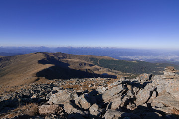 Mountain ridge, covered with grass, stretching to the wooded hills