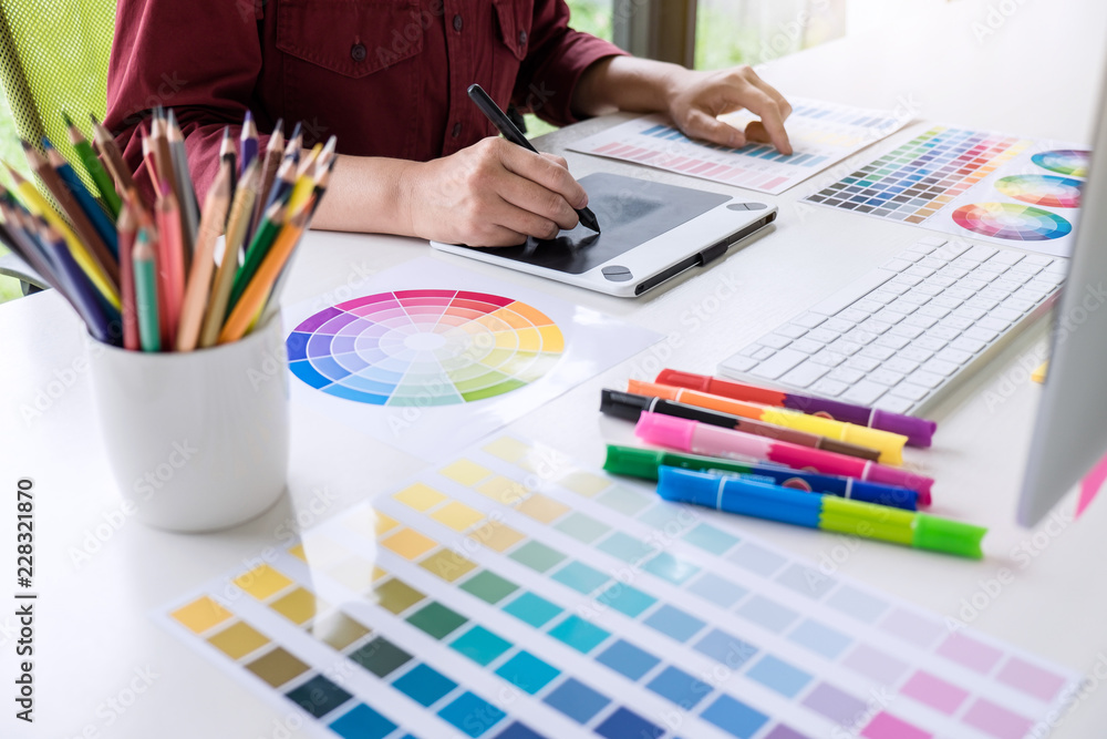 Poster image of female creative graphic designer working on color selection and drawing on graphics tablet 