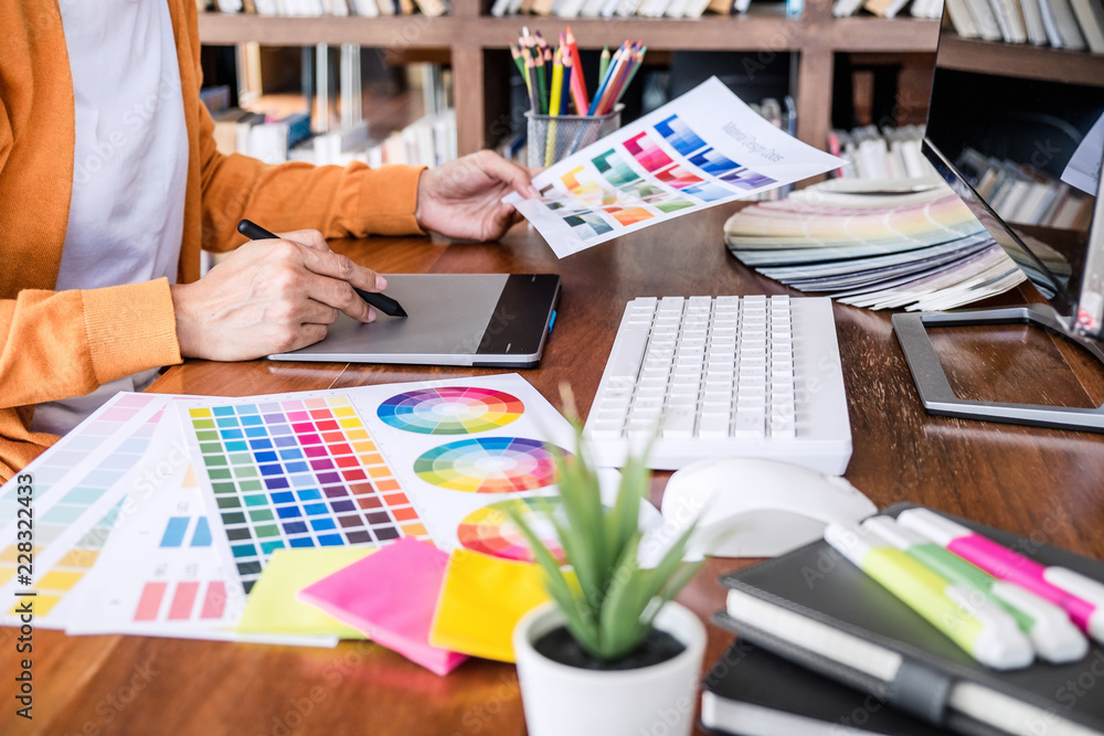 Poster Image of female creative graphic designer working on color selection and drawing on graphics tablet at workplace with work tools and accessories