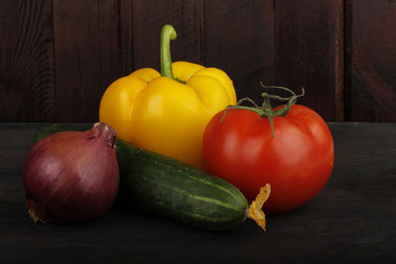 cucumber, tomato, red onion and yellow pepper on wooden background