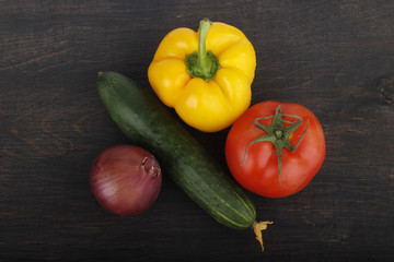 cucumber, tomato, red onion and yellow pepper on wooden background