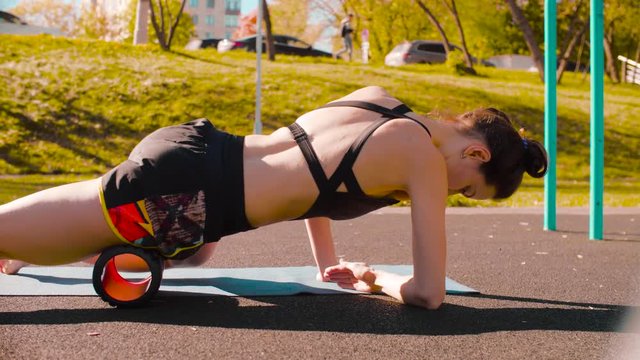 Woman doing self massage of the legs with a roll. Sunny day, golden autumn
