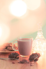 Christmas scene with a cup of hot cocoa, chocolate chip cookies and almonds with cristmas lights / Green Background and wooden table, with text and copy space, bokeh effect