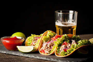 Photo of Mexican tacos with ground meat, beef, beans, onions and salsa on wooden background....