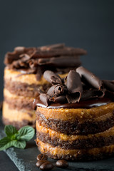 Chocolate cakes on black slatter board with mint, coffee beans on dark background, closeup photo. Fresh, tasty dessert food concept. 