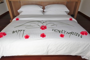 View of a bed with flowers arranged on top for a honeymoon