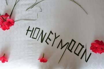 View of a bed with flowers arranged on top for a honeymoon