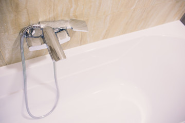 In the bathroom, open shower mixer has attached to the wall bracket, tinted black and white image,...