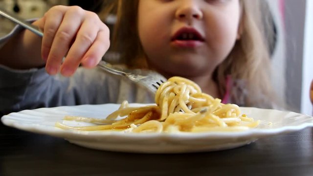 Little girl is eating spaghetti