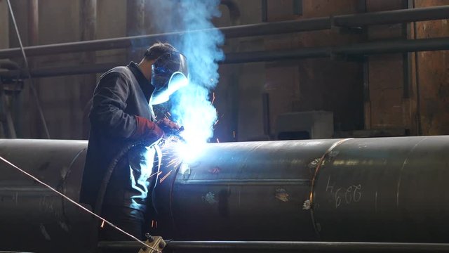 Man welding metal tube with glowing sparks