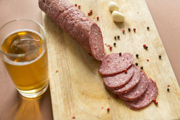 stick and pieces of smoked sausage on a cutting Board with spices a glass of beer