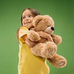 Happy teen girl standing, smiling with toy bear isolated on trendy studio background. Beautiful...